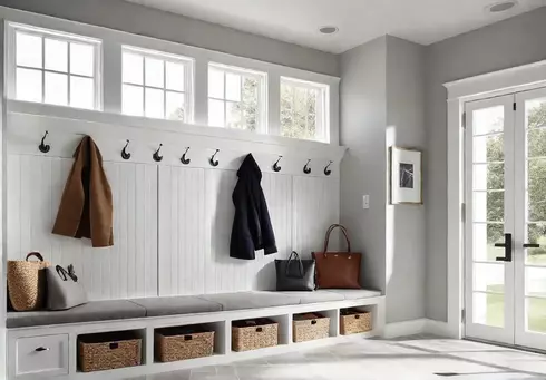 A cozy mudroom with light gray textured tile flooring white builtin storagefeat