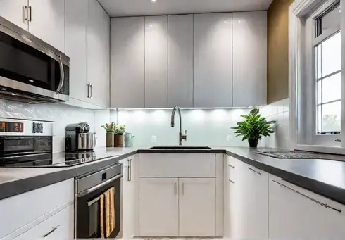 A small brightly lit kitchen with light countertops and a colorful backsplashfeat